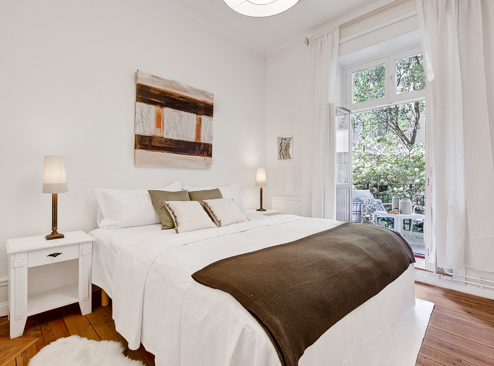 Example of a large master medium tone wood floor bedroom design in Stockholm with white walls and no fireplace