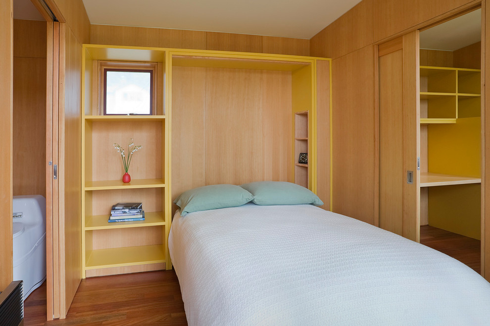 Ispirazione per una piccola camera degli ospiti minimalista con pareti gialle, pavimento in legno massello medio e nessun camino