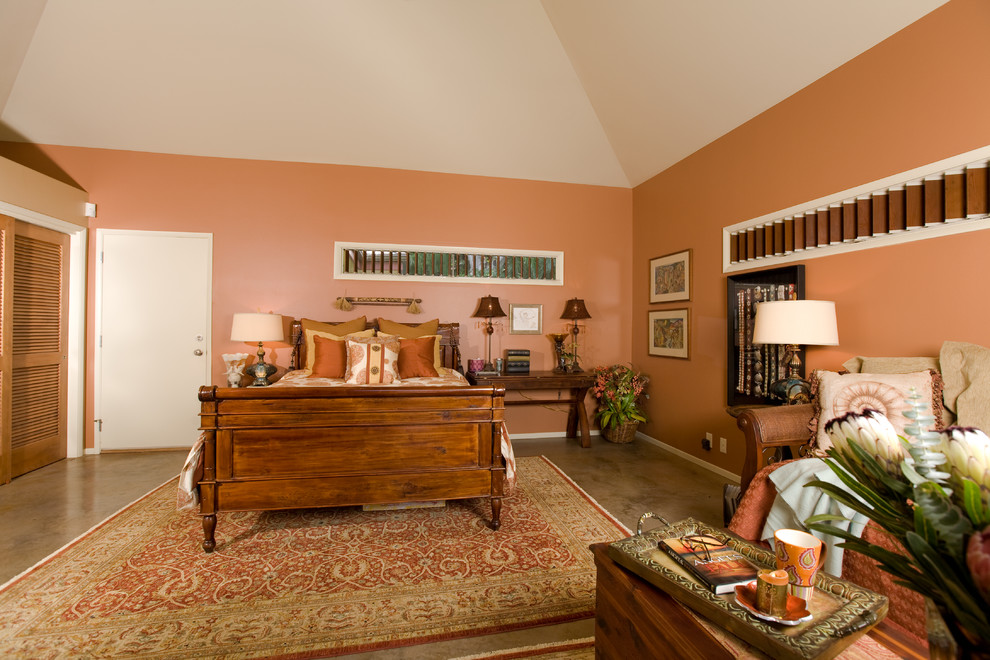 Idée de décoration pour une grande chambre d'amis ethnique avec un mur orange, sol en béton ciré et un sol marron.