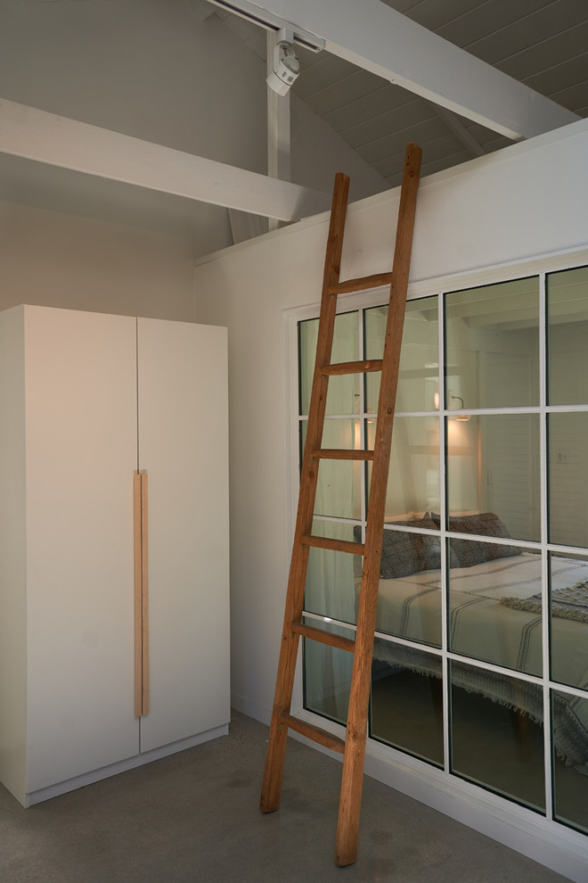 Aménagement d'une petite chambre parentale moderne avec un mur blanc, sol en béton ciré, une cheminée d'angle, un manteau de cheminée en plâtre et un sol gris.