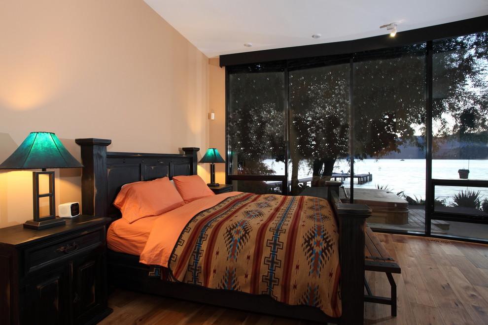 Foto di una camera matrimoniale american style con pareti beige e pavimento in legno massello medio