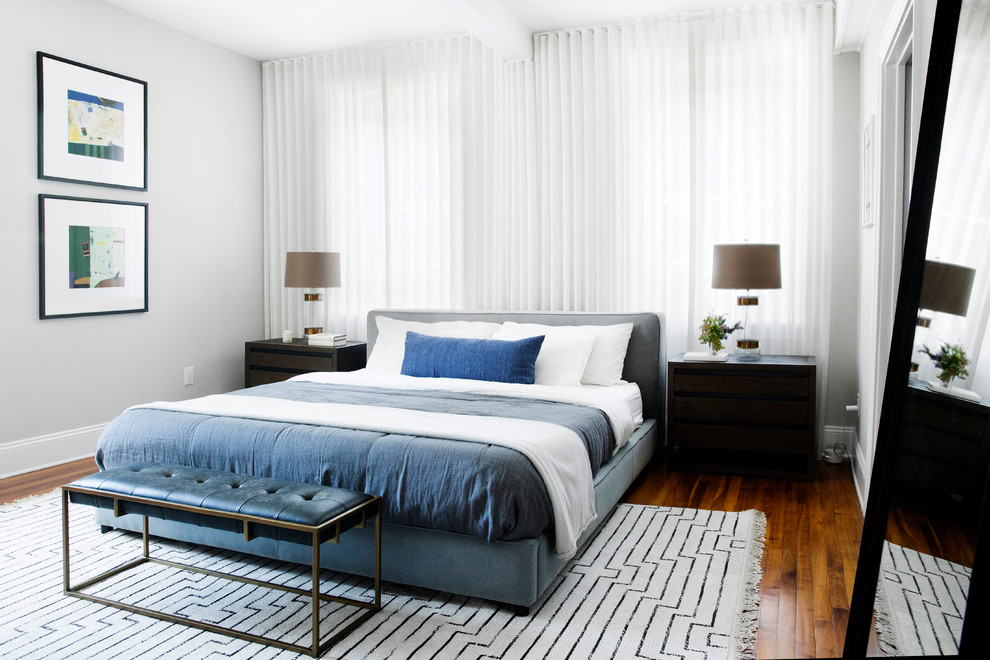 Foto di una camera da letto minimal con pareti grigie, parquet scuro e pavimento marrone