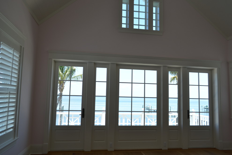 Ejemplo de dormitorio principal costero con paredes rosas y suelo de madera en tonos medios