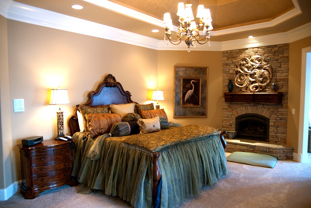 Стильный дизайн: большая хозяйская спальня в средиземноморском стиле с бежевыми стенами, ковровым покрытием, стандартным камином, фасадом камина из камня и бежевым полом - последний тренд