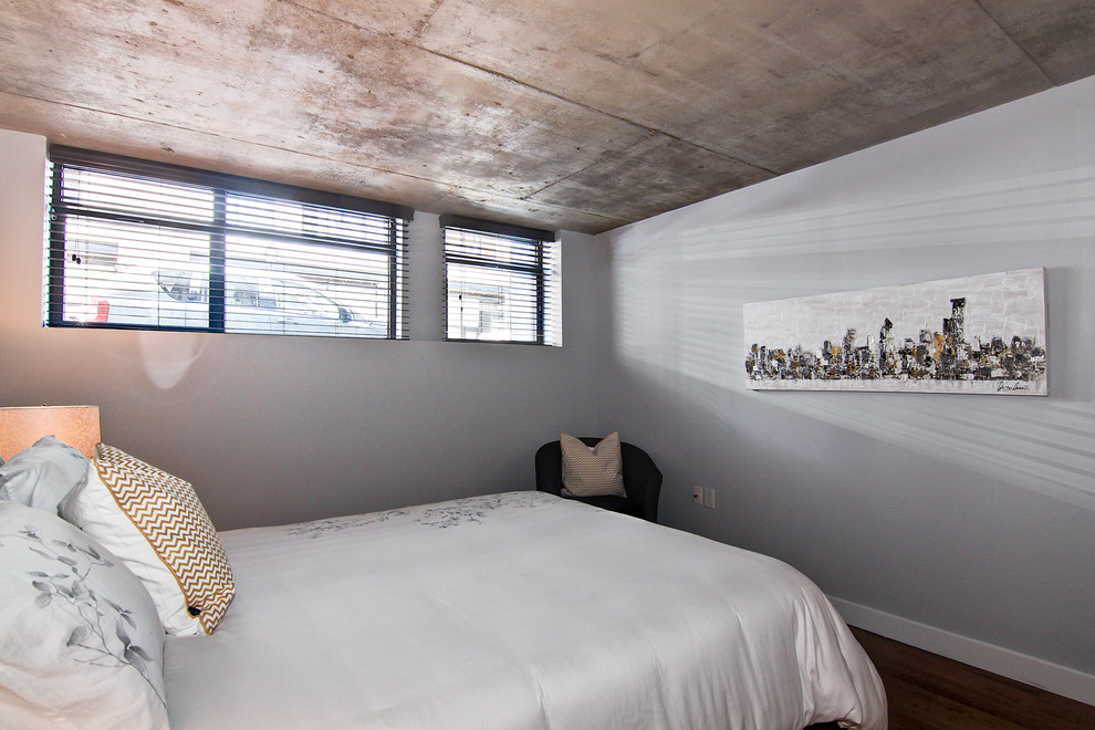 Idee per una camera matrimoniale industriale di medie dimensioni con pareti grigie e pavimento in legno massello medio