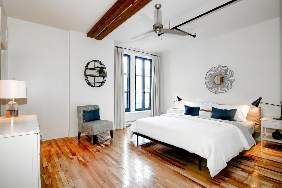 Imagen de dormitorio principal actual grande sin chimenea con paredes blancas y suelo de madera en tonos medios