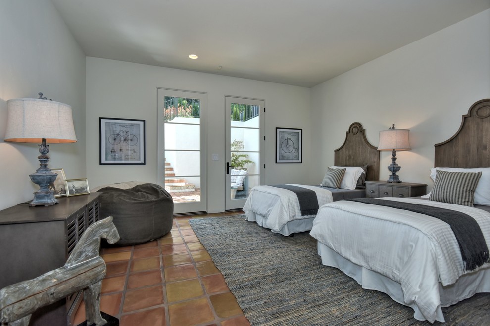 На фото: большая гостевая спальня (комната для гостей) в средиземноморском стиле с белыми стенами, полом из терракотовой плитки и коричневым полом без камина