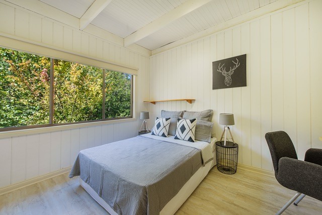 Immagine di una camera matrimoniale country di medie dimensioni con pareti bianche, pavimento in legno massello medio e pavimento marrone