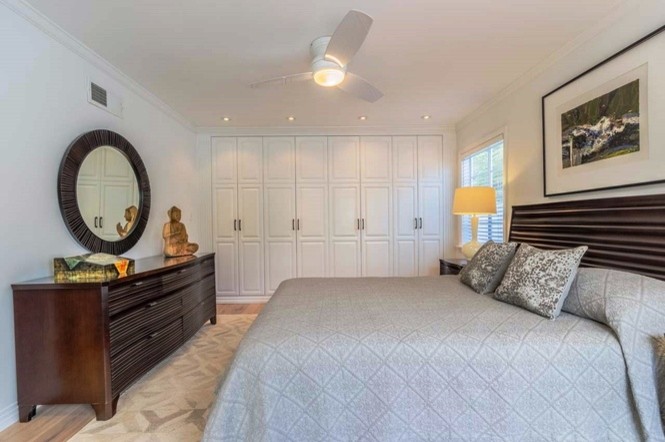 This is an example of a large midcentury guest bedroom in San Diego with white walls and light hardwood flooring.
