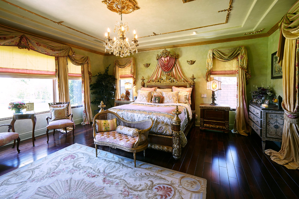 На фото: большая хозяйская спальня в классическом стиле с зелеными стенами, темным паркетным полом, стандартным камином, фасадом камина из штукатурки и коричневым полом с