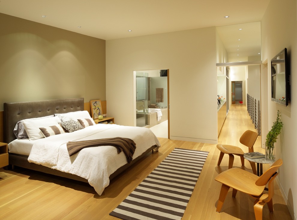 Contemporary grey and brown bedroom in Los Angeles with grey walls and light hardwood flooring.