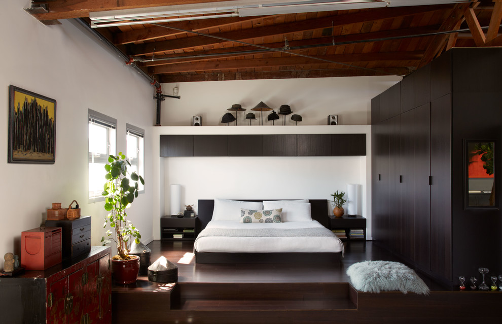 Modelo de dormitorio principal contemporáneo grande sin chimenea con paredes blancas y suelo de madera oscura