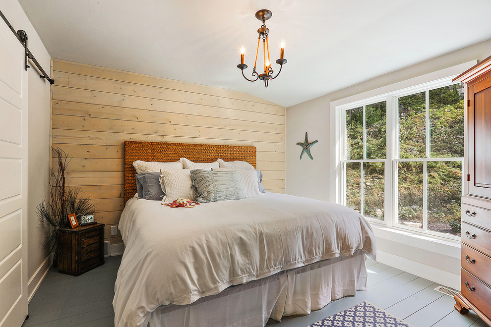 Modelo de habitación de invitados costera de tamaño medio sin chimenea con paredes negras, suelo gris y suelo de madera pintada