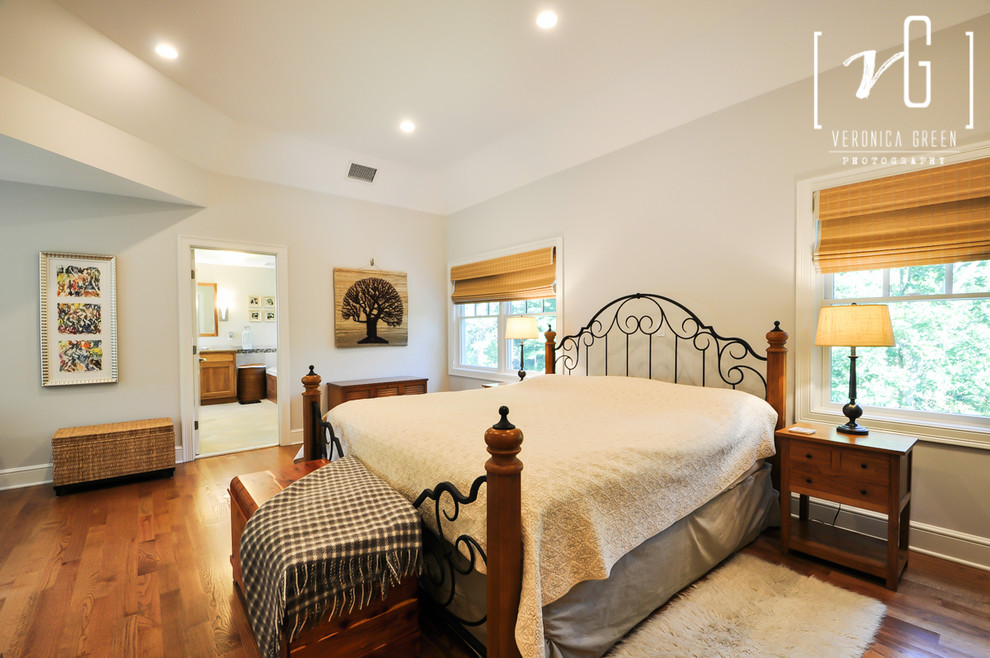 Modelo de dormitorio principal clásico renovado grande sin chimenea con paredes grises y suelo de madera en tonos medios
