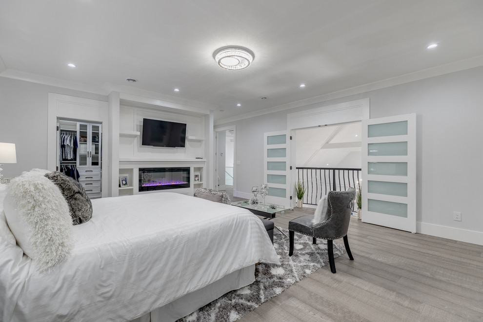 バンクーバーにある広いコンテンポラリースタイルのおしゃれな主寝室 (グレーの壁、淡色無垢フローリング、横長型暖炉、木材の暖炉まわり、茶色い床) のインテリア
