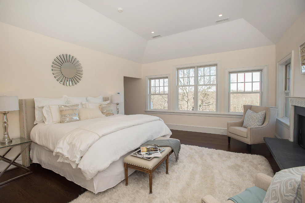 Photo of a large classic master bedroom in New York with multi-coloured walls, dark hardwood flooring, a standard fireplace, a stone fireplace surround and brown floors.