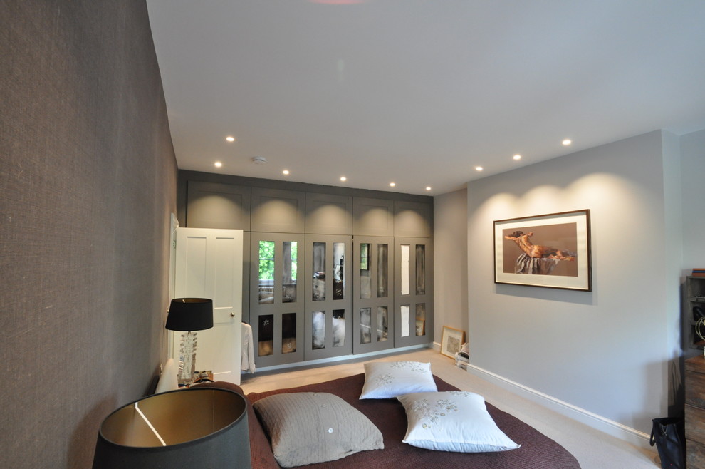 Medium sized contemporary master and grey and cream bedroom in London with grey walls and carpet.