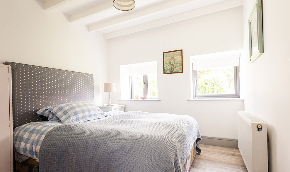Imagen de habitación de invitados costera con paredes blancas y suelo de madera clara