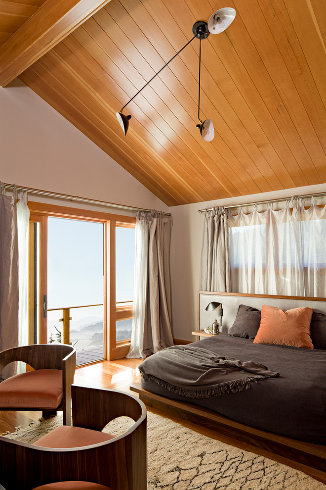 Modelo de dormitorio contemporáneo con paredes blancas y suelo de madera en tonos medios
