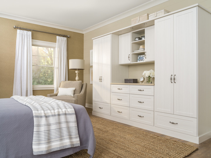 Imagen de dormitorio principal clásico de tamaño medio con paredes beige, suelo laminado y suelo marrón