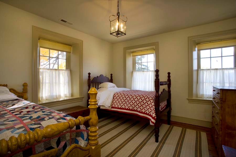 Ispirazione per una camera degli ospiti stile americano di medie dimensioni con pareti beige, pavimento in legno massello medio e nessun camino