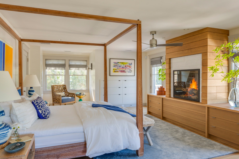 Imagen de dormitorio principal marinero con paredes blancas, suelo de madera clara y estufa de leña