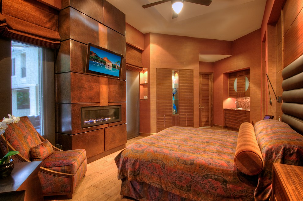 На фото: хозяйская спальня среднего размера в современном стиле с коричневыми стенами, светлым паркетным полом, горизонтальным камином и фасадом камина из металла с