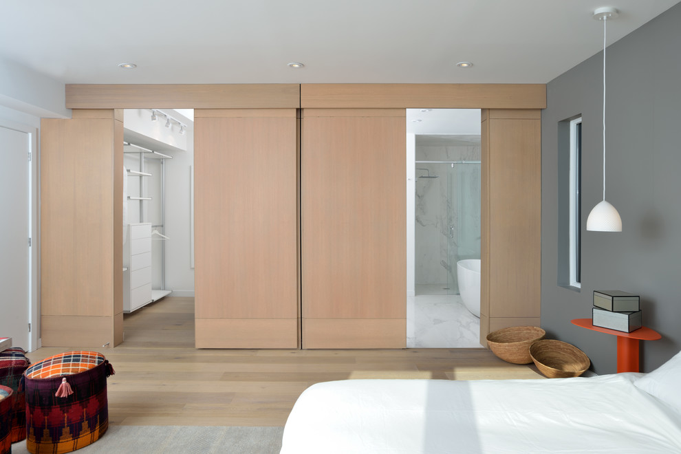 Diseño de dormitorio actual de tamaño medio con paredes grises, suelo de madera clara y suelo beige