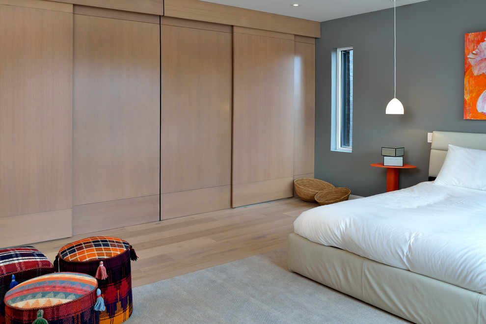 Foto de dormitorio principal actual de tamaño medio con paredes grises, suelo de madera clara y suelo beige