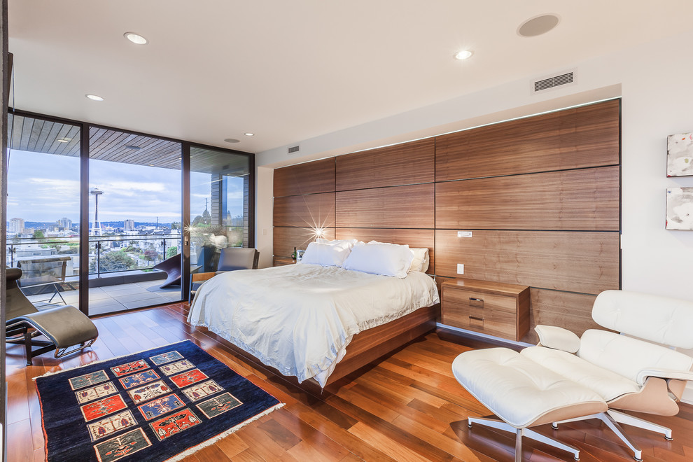 Imagen de dormitorio principal contemporáneo grande con paredes blancas, suelo de madera en tonos medios y todas las chimeneas