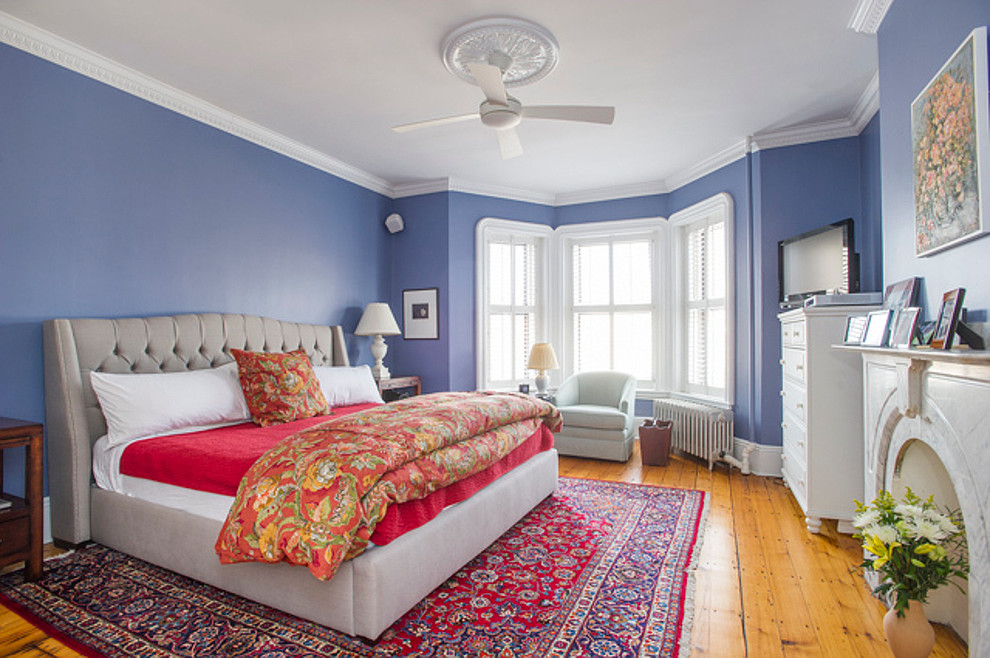 Foto de habitación de invitados clásica renovada de tamaño medio con paredes púrpuras, suelo de madera clara, todas las chimeneas, marco de chimenea de piedra y suelo beige