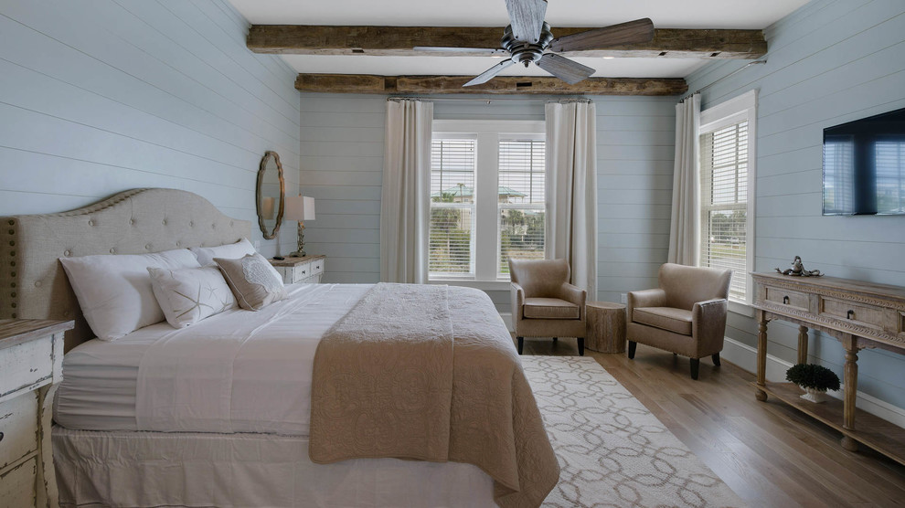 Ejemplo de dormitorio principal marinero grande con paredes azules y suelo de madera clara