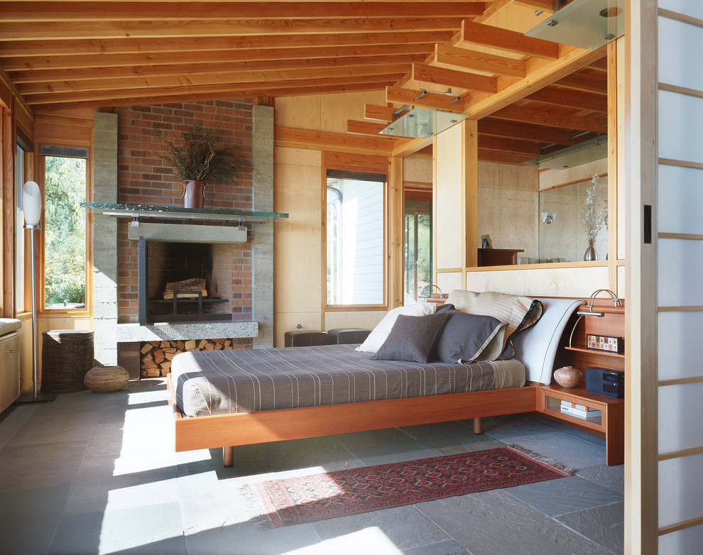Пример оригинального дизайна: спальня в стиле лофт с стандартным камином и фасадом камина из кирпича