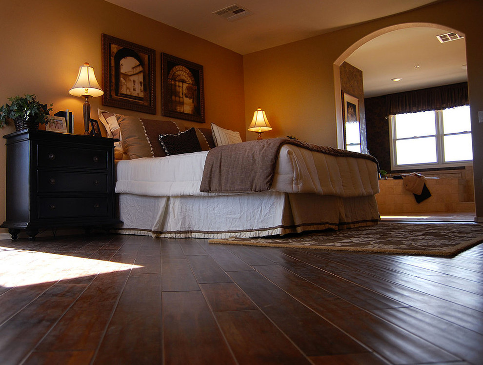 Modelo de dormitorio tradicional grande con paredes beige y suelo de madera oscura