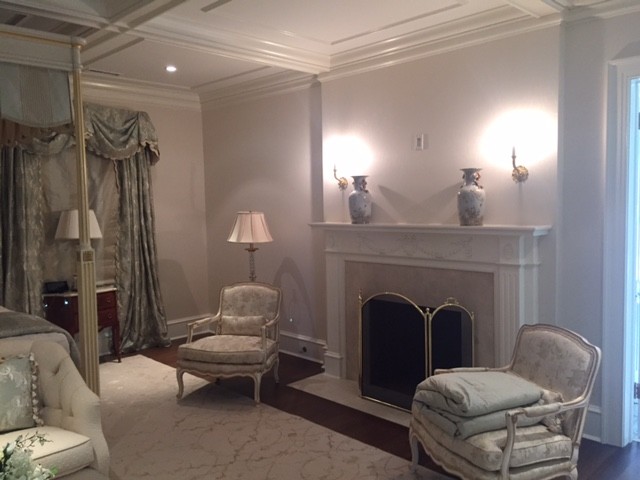 Cette photo montre une chambre parentale victorienne de taille moyenne avec un mur beige, parquet foncé, une cheminée standard, un manteau de cheminée en plâtre et un sol marron.
