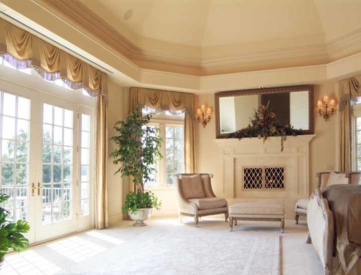 На фото: большая хозяйская спальня в классическом стиле с белыми стенами, ковровым покрытием, стандартным камином и фасадом камина из штукатурки с