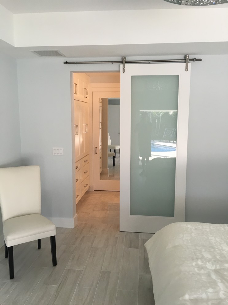 Modelo de habitación de invitados actual de tamaño medio sin chimenea con paredes azules, suelo de madera clara y suelo gris