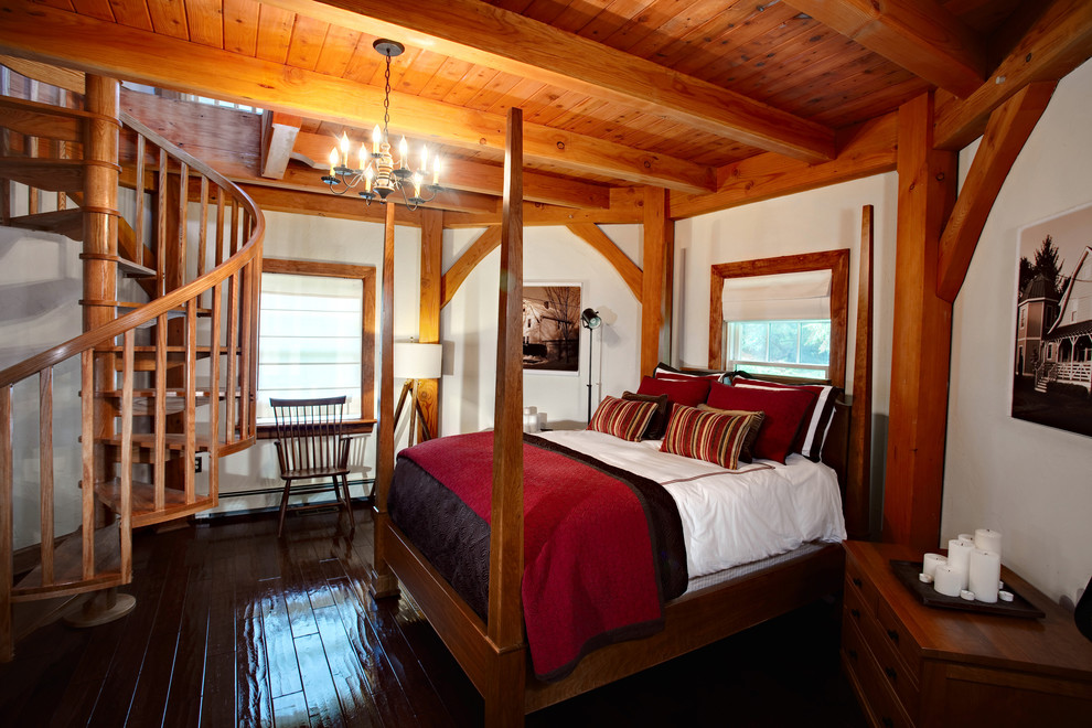Foto på ett stort lantligt sovrum, med vita väggar och mörkt trägolv