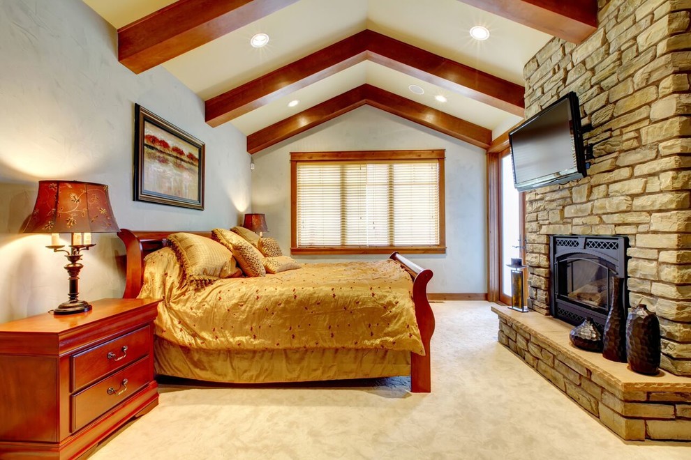 Inspiration for a large timeless master carpeted bedroom remodel in Denver with gray walls, a standard fireplace and a stone fireplace