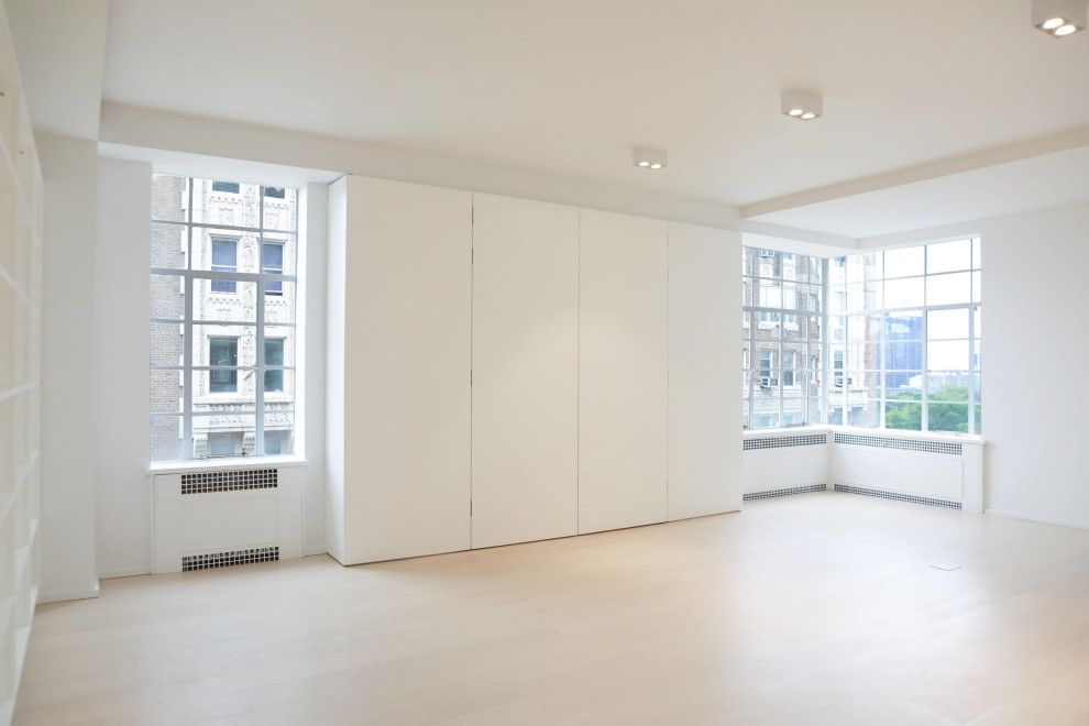 Idée de décoration pour une très grande chambre parentale minimaliste avec un mur blanc, parquet clair et un sol marron.