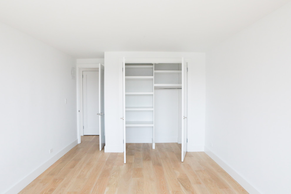 Cette image montre une petite chambre minimaliste avec un mur blanc, parquet en bambou et un sol marron.