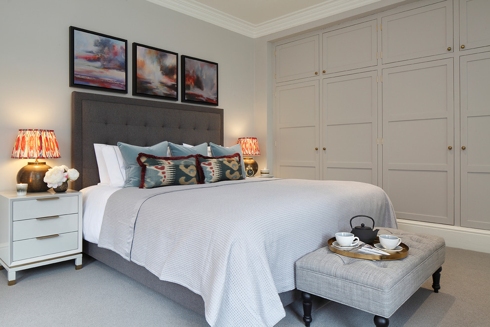 На фото: большая хозяйская спальня в стиле неоклассика (современная классика) с серыми стенами, ковровым покрытием, серым полом, стандартным камином и фасадом камина из дерева с