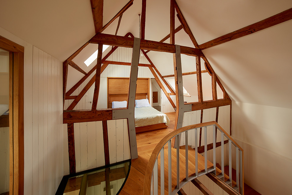 Ejemplo de dormitorio principal rústico de tamaño medio con paredes blancas, suelo de madera en tonos medios y suelo marrón