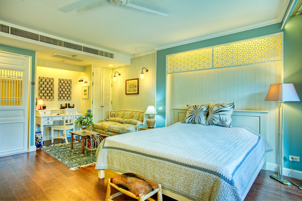 Imagen de dormitorio principal contemporáneo sin chimenea con paredes azules, suelo de madera en tonos medios y con escritorio