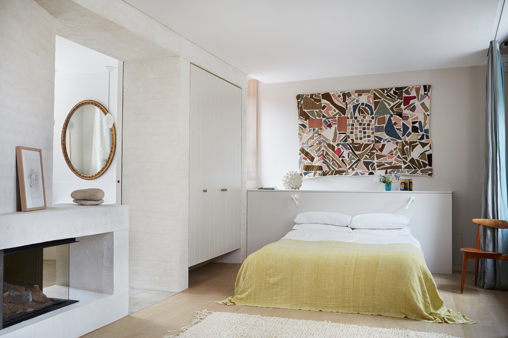 Источник вдохновения для домашнего уюта: хозяйская спальня среднего размера в современном стиле с белыми стенами, бежевым полом, светлым паркетным полом, двусторонним камином и фасадом камина из кирпича