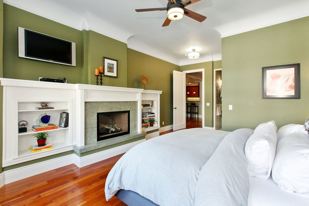 Cette photo montre une chambre parentale chic de taille moyenne avec un mur vert, parquet clair, une cheminée standard et un manteau de cheminée en pierre.
