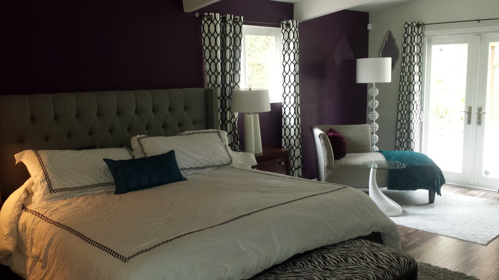 Esempio di una camera matrimoniale minimalista con pareti viola e pavimento in laminato