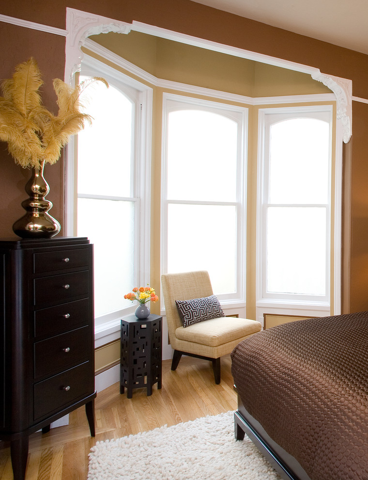 Foto de dormitorio principal tradicional de tamaño medio sin chimenea con paredes marrones, suelo de madera clara y suelo beige