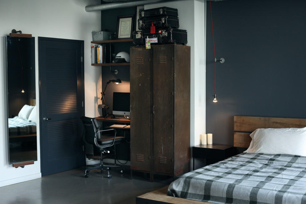 Ejemplo de dormitorio industrial sin chimenea con paredes azules, suelo de cemento y con escritorio