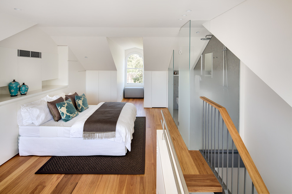 Design ideas for a medium sized contemporary mezzanine loft bedroom in Sydney with white walls, medium hardwood flooring and no fireplace.